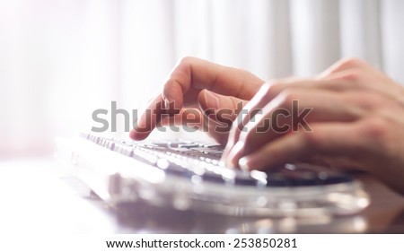 man typing on a keyboard with a white keyboard (shallow depth of field)