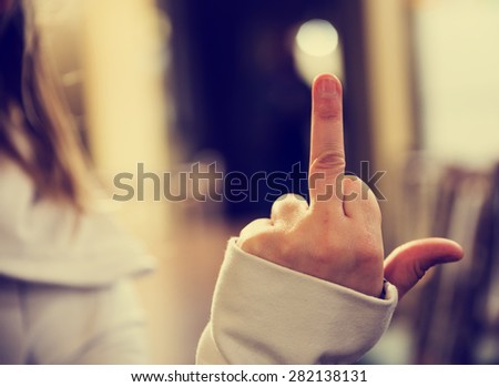 young woman hand positioned flipping-off with retro instagram filter (shallow depth of field)