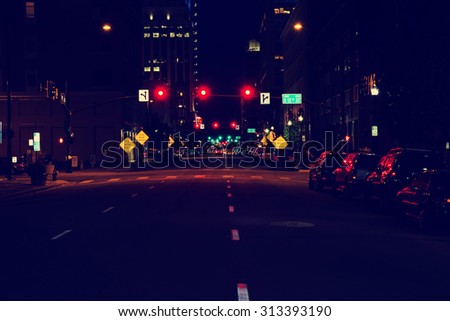 looking down the center of a dark city street with limited human and vehicle traffic with a toned instagram filter