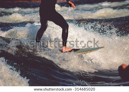 male surfer riding a wave on a white water river park with a retro vintage instagram filter
