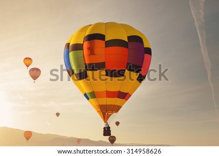 a large hot air balloon flies over the sky during sunrise or sunset with a bright sun glare across the sky