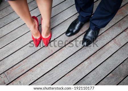 The legs of a stylish man and woman in   red high heels classic