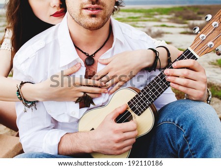 Couple hands hold ukulele guitar