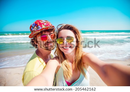 Beautiful couple in love doing self on a tropical beach, enjoy the holidays, sunbathe and have fun.