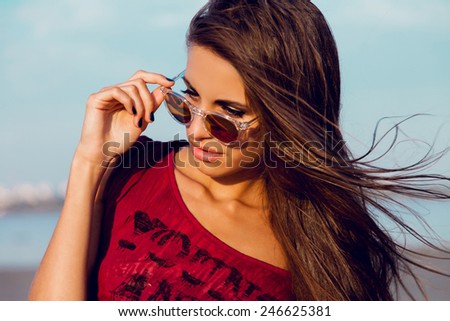 Attractive tanned fitness woman  with beautiful big eyes and red lips posing on the tropical evening beach . Wet hair and perfect skin .Close up portrait .