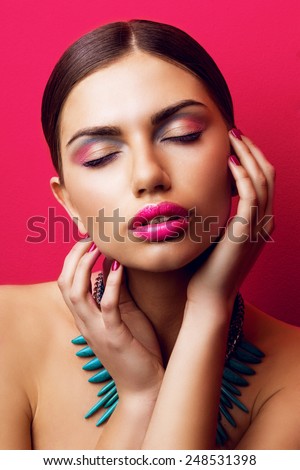 Close up fashion portrait of seductive woman  with sexy big  pink lips .  Model \
closing  her eyes and touch perfect skin. Colorful beauty photo.