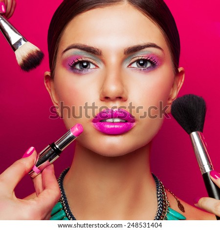 Colorful fashion beauty portrait of young woman with  bright make up , big pink  full lips and effect necklace .Beautiful young female getting her make-up done against color background.