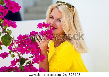 Beautiful  pretty  blonde lady with pink full lips posing near perfect flowers sniffs it  and enjoy their fragrance .Wearing sunglasses .