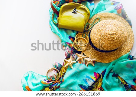 Stylish beach accessories  . Straw hat , little leather green bag and a lot of bamboo bracelets . Summer lifestyle. Bright colors. Vacation mood.