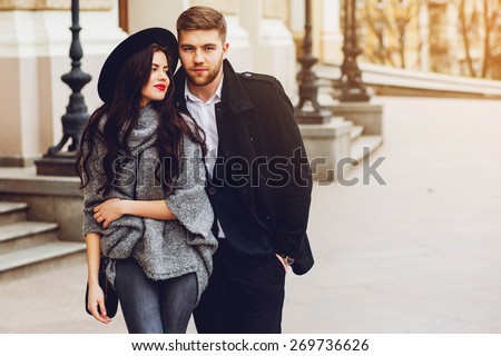 Young fashion couple posing on the old  street in  sunny fall . Pretty beautiful  woman and her  handsome stylish boyfriend  hugging  on the street. Creamy  autumn sunlight.