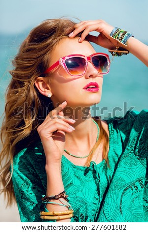 Stunning colorful outdoor summer portrait of pretty young blonde beautiful woman in  cool sunglasses posing on the sunny tropical  beach.