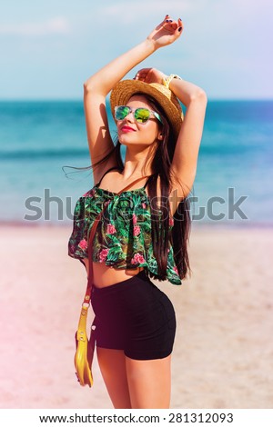 Outdoor summer  lifestyle portrait of  perfect fit   smiling  woman with perfect body  having fun  on the tropical  beach wearing straw hat.    Bright colors. Happy mood.
