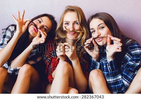 Close up indoor lifestyle portrait of three funny young  friends have fun and  pretending faces. Home party mood. Wearing plaid shirt.