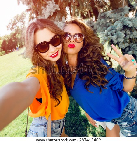 Close up lifestyle  image  of two best friends having fun and making self  portrait  together.    Bright colors.Wearing casual outfit.