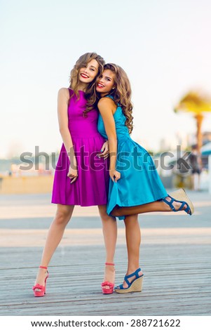 Two pretty elegant women  in evening cocktail dresses walking  along the promenade . Enjoying time together and have fun.