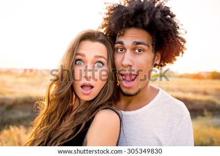 Outdoor portrait of  cheerful  young international couple shoes crazy  faces .  Friends having fun , emotional people, making self portrait.