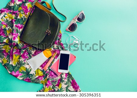 Close up lifestyle photo of hipster student accessories . Still life of random objects of modern girl / woman. Leather bag, camera, Sunglasses,t, Aerial view. Sunny summer colors.  Tropical print.