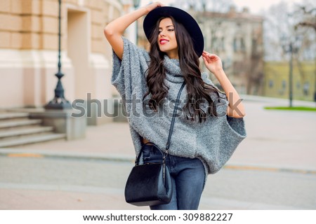 Outdoor fashion portrait of glamour sensual young stylish lady wearing trendy fall outfit , black hat , grey sweater and leather bag. Cold season.Red lips. Warm  clothes.