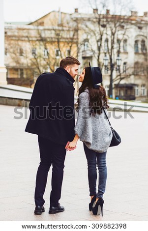 Close up fashion portrait of young stylish glamour girl and guy in love . Couple walking down the street in sunny fall . Warm autumn colors. Wearing black trendy outfit .