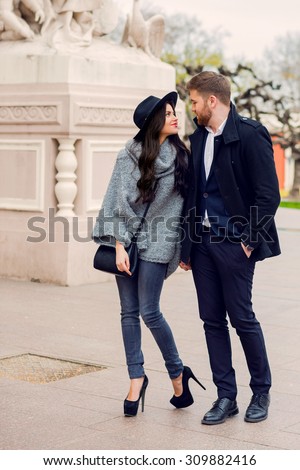 Close up fashion portrait of young stylish glamour girl and guy in love . Couple walking down the street in sunny fall . Warm autumn colors. Wearing black trendy outfit .