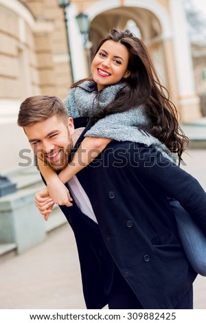 Outdoor fall portrait of fashionable pretty young couple wearing trendy monochrome outfit . Two lovers posing against theater background in autumn sunlight.