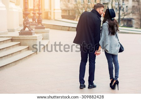 Stylish young couple walking on european autumn streets , have fun and hugging. Wearing trendy season outfit. Creamy  warm colors.