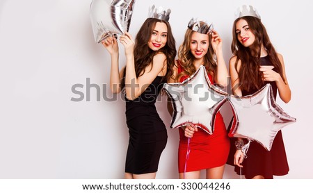 Three beautiful elegant women celebrate birthday  and dancing. Best friends wearing black stylish evening dress, high heel shoes ,crown on head .Bright make up, red lips. Inside.