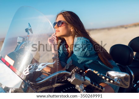 Young amazing sexy woman  sitting on  motorbike on the beach, wearing stylish crop top , shirts, have perfect fit slim tamed body and long hairs. Outdoor lifestyle   portrait.