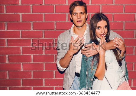 Young friends funny guys active people have fun together woman and man, girl and guy summer urban casual style. Pink brick wall, spring  outfit, hipsters having fun, surprised faces .