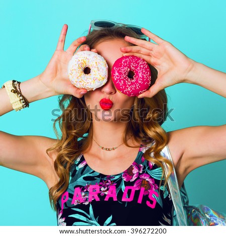 Beauty blonde fashion model girl  holding colorful pink donuts against  her eyes. Funny joyful woman with sweets, dessert. Diet, dieting concept. Junk food. Bright colors.