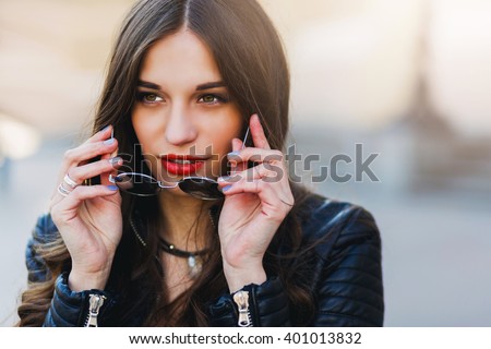 Close up fashion portrait of pretty seductive young woman with sunglasses, posing outdoor. Red lips, wavy hairstyle.