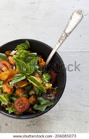 alternative vegan salad with basil, carrots chips, tomatoes in japanese bowl with white wooden background