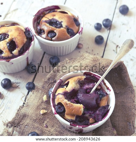 vintage polaroid instagram of clafoutis with blueberries and cherries on ceramic ramekins on rustic white vintage background with canvas and fork
