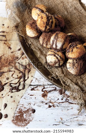 homemade coconut macaroons with dripped dark chocolate and cocoa powder on tray with chocolate backdrop and vintage background