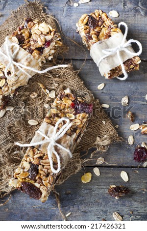 homemade rustic granola bars with dried fruits and handmade packaged on old bowl on vintage blue wooden background