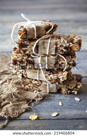 stack of homemade granola bars with dried fruits and handmade packaged on vintage blue wooden background