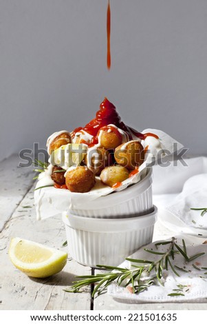 balls of fried potatoes with dripping ketchup splash, lemon and rosemary