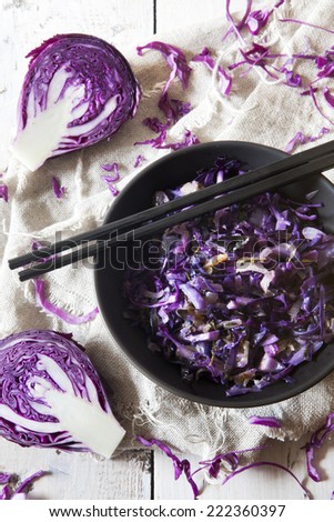 sauteed purple cabbage on black bowl with japanese chopsticks on white wooden table with napkin