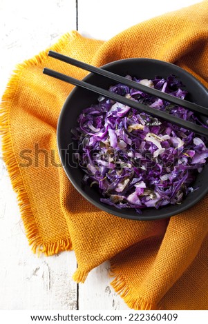 sauteed purple cabbage on bowl with japanese chopsticks and orange napkin on table