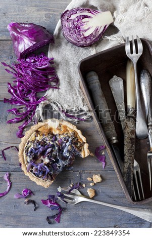 homemade purple cabbage and cheese rustic quiche and vintage box with silverware on table with sliced raw cabbage
