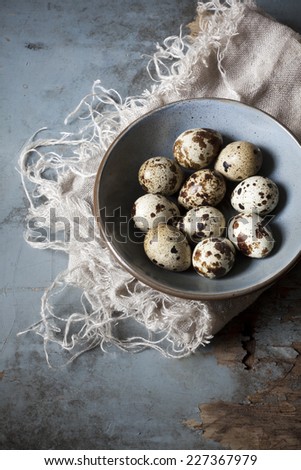 quail eggs on bowl on blue wooden rustic table with old frayed cloth