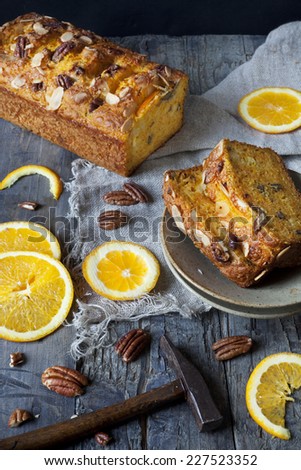 slices of citrus cake on plate on table with pecan walnuts and orange slices and little hammer