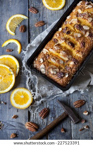 citrus plumcake with pecan walnuts on mold on table with fresh orange slices and hammer
