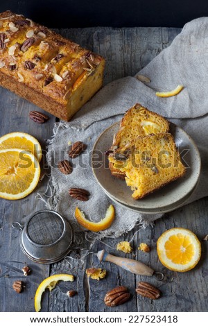 slices of citrus cake on plate on rustic table with pecan walnuts orange slices and vintage strainer