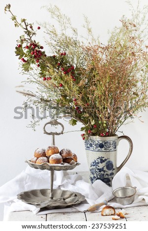 coconut sweets on vintage dessert stand with wild flowers bouquet on porcelain pitcher on white table