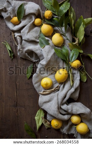 group of fresh lemons with leaves on wooden table with cloth