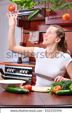 happy woman is cooking salad out of flying vegetables