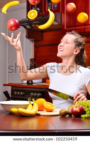 happy woman is cooking fruit salad out of flying fruits