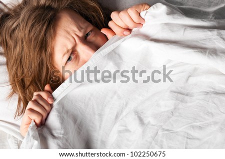 angry woman is lying in bed under blanket and doesn\'t want to wake up