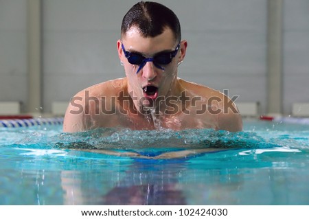 man swims using the breaststroke in indoor pool